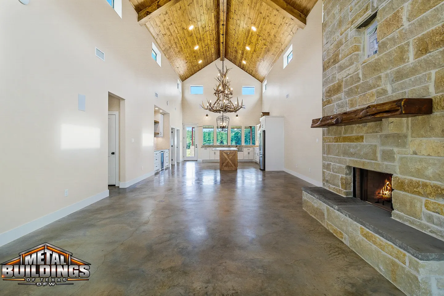 Open living area with wood ceiling and stone fireplace — Metal Buildings of Texas