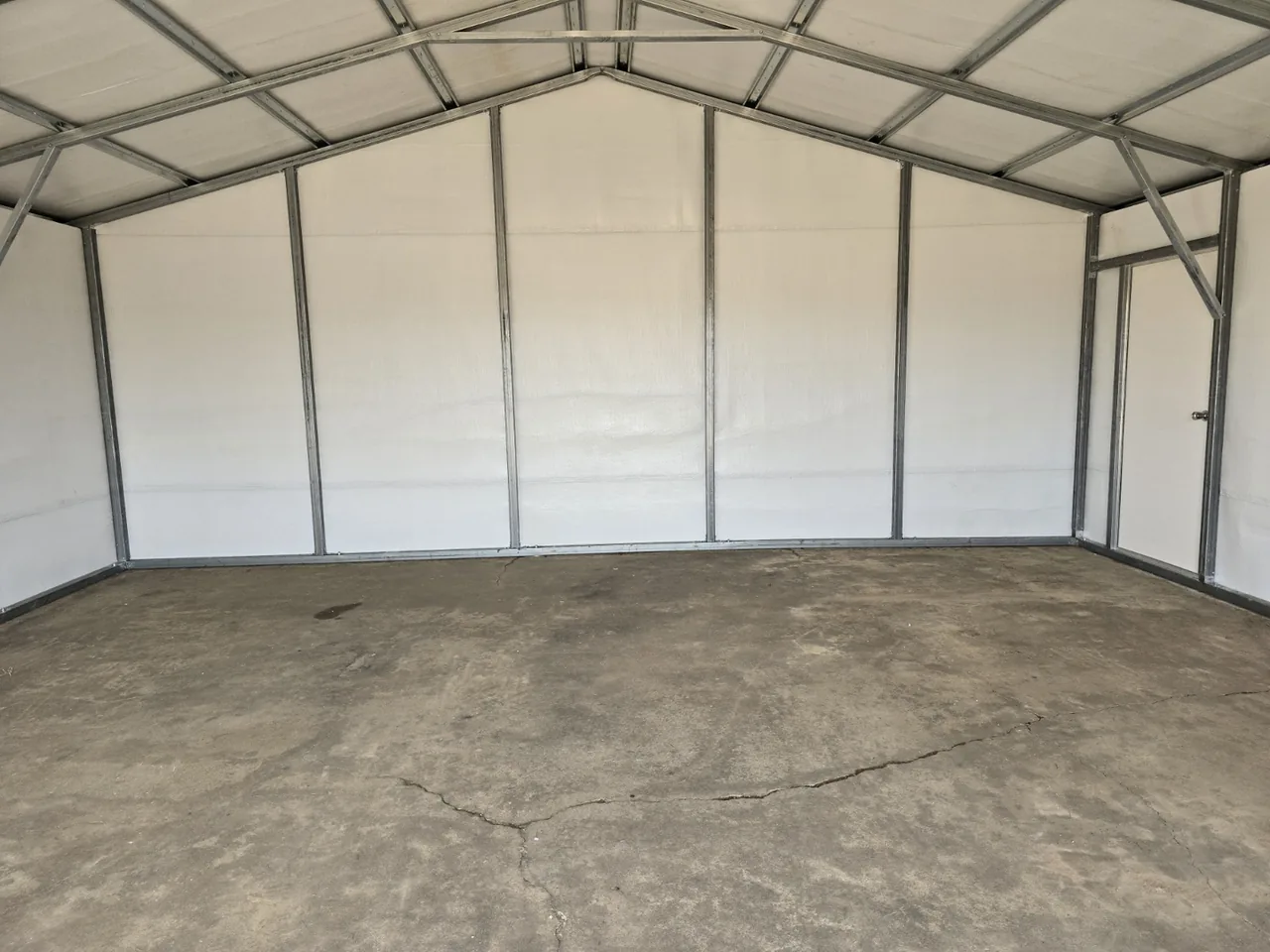 Unfinished metal building interior with visible framing and a concrete floor