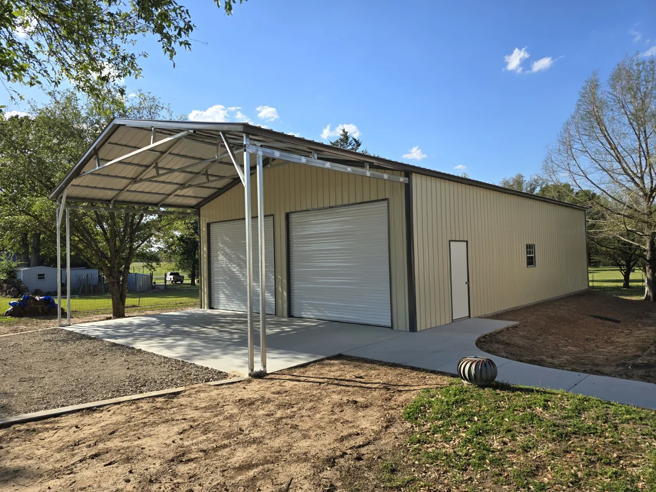 Long metal building with an overhead door and covered front bay