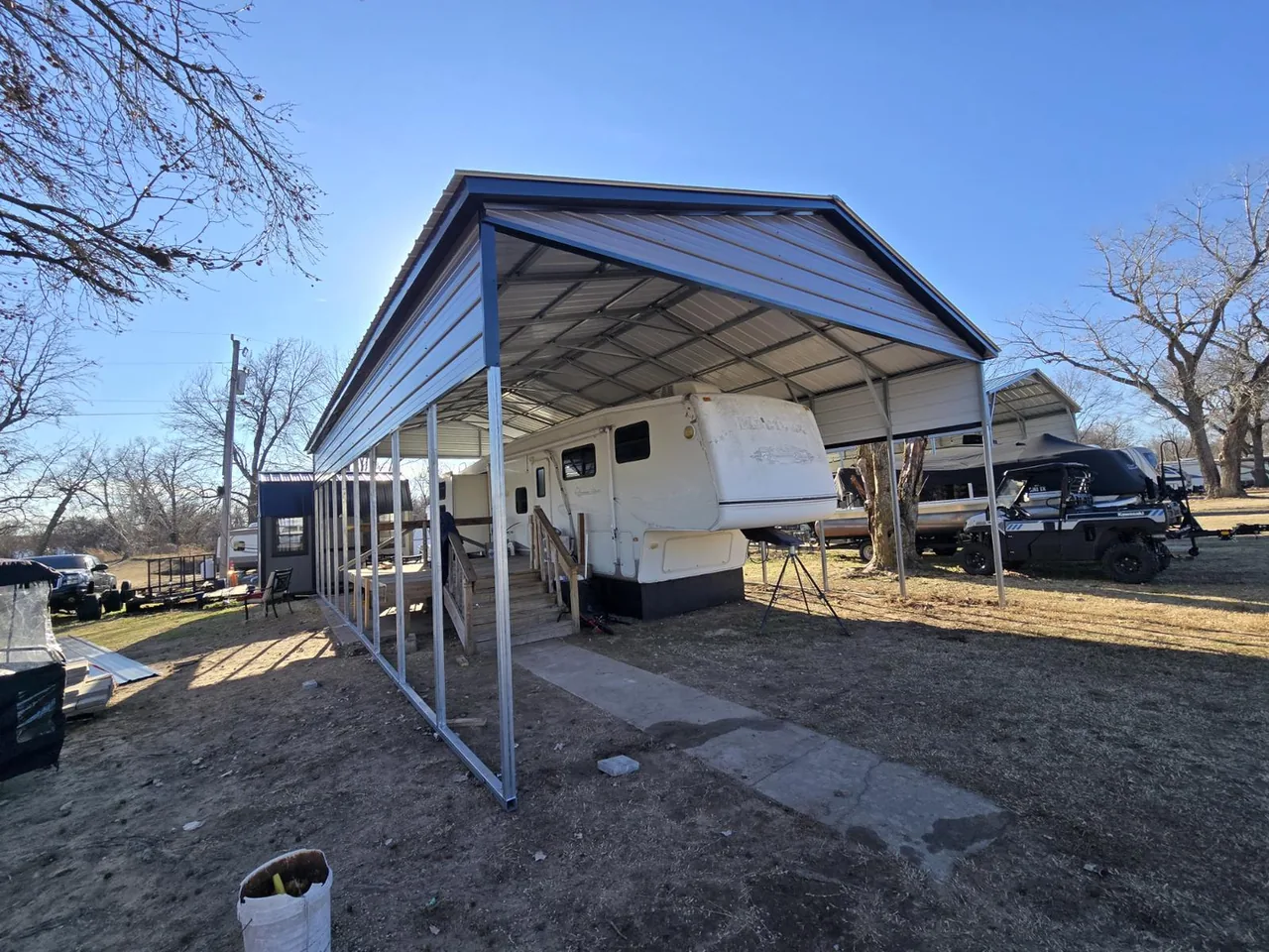Recreational vehicle parked beneath an open-sided metal cover